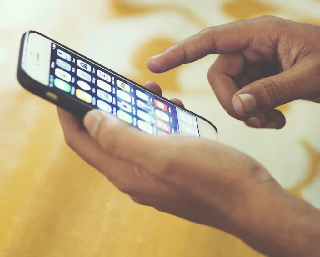 A person holding a smartphone and tapping the screen with a grid of app icons, representing a client using a branded accounting portal app