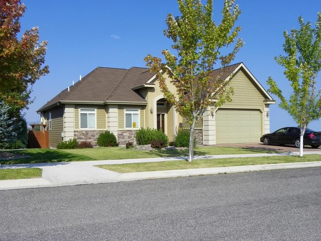 Suburban single-family home with a two-car garage, stone accents and landscaped front yard on a quiet street, a residential property listing