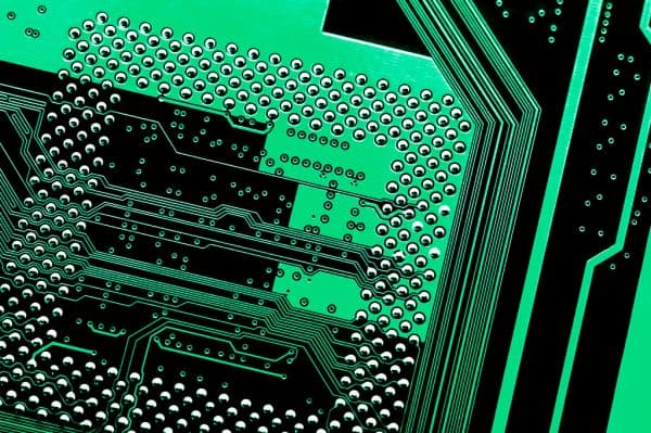 Extreme close-up of a green computer motherboard with a dense grid of solder points and circuit traces