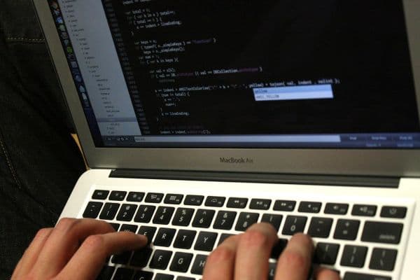 Close-up of a developer's hands typing source code in an editor on a laptop, building a backend integration