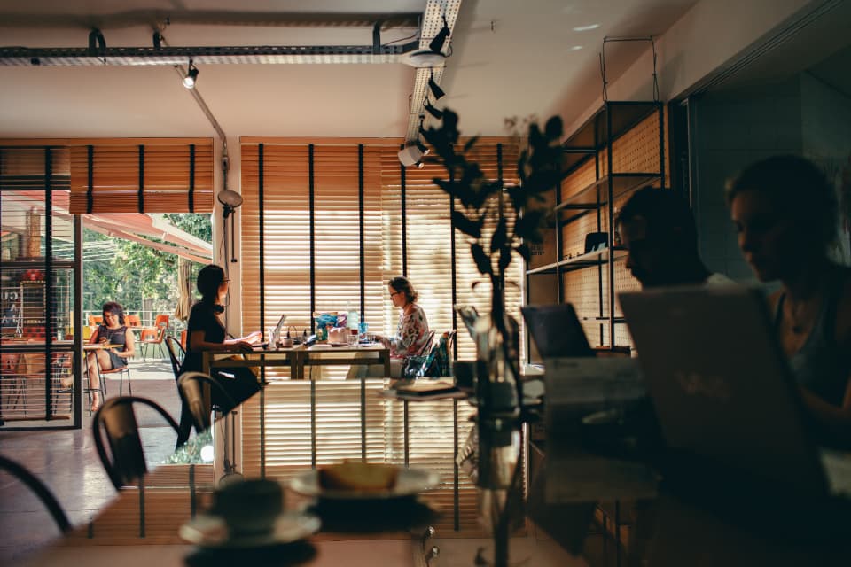 People working on laptops in a warm coworking space, representing a sales team responding to incoming CRM leads