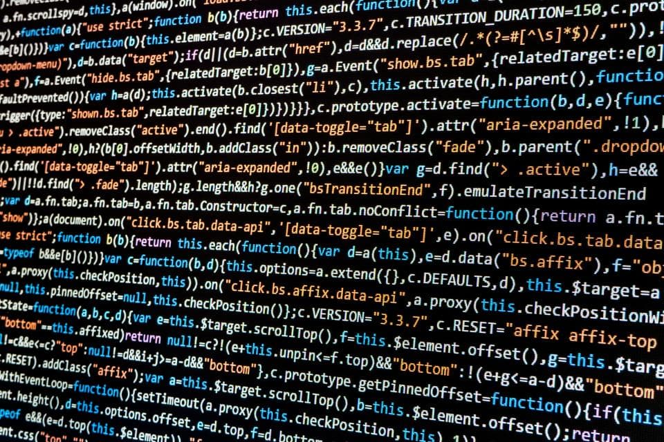 Computer screen filled with colourful syntax-highlighted JavaScript source code on a dark background