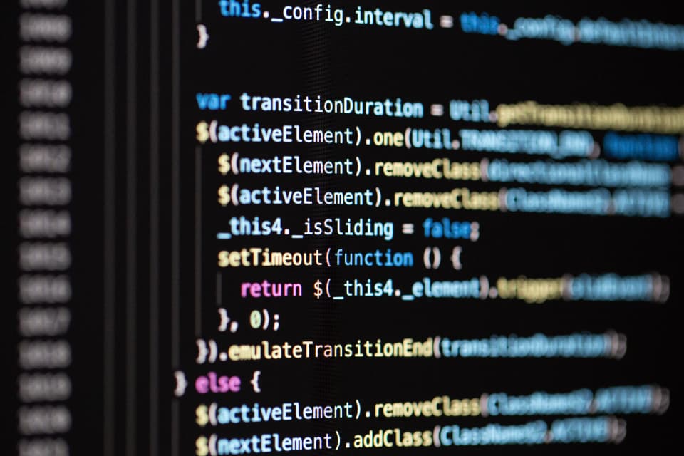 Close-up of a dark monitor showing syntax-highlighted programming code with functions and variables