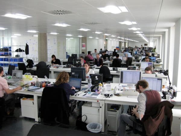 Busy open-plan corporate office with rows of staff at desktop computers, representing an enterprise Microsoft 365 workplace