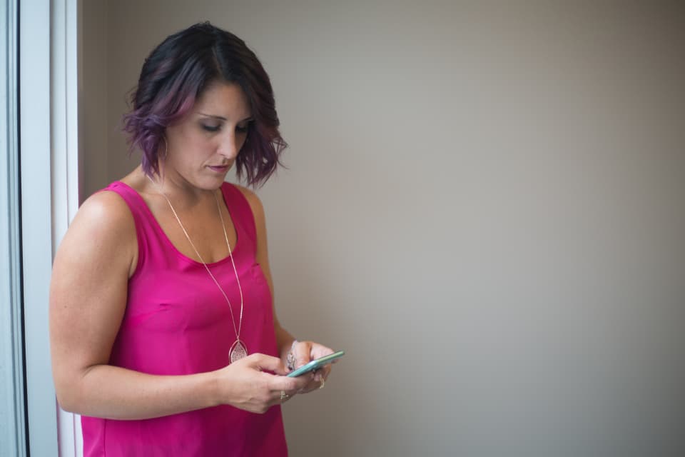 Person tapping a reply on a smartphone by a window, illustrating two-way WhatsApp messaging for order confirmation