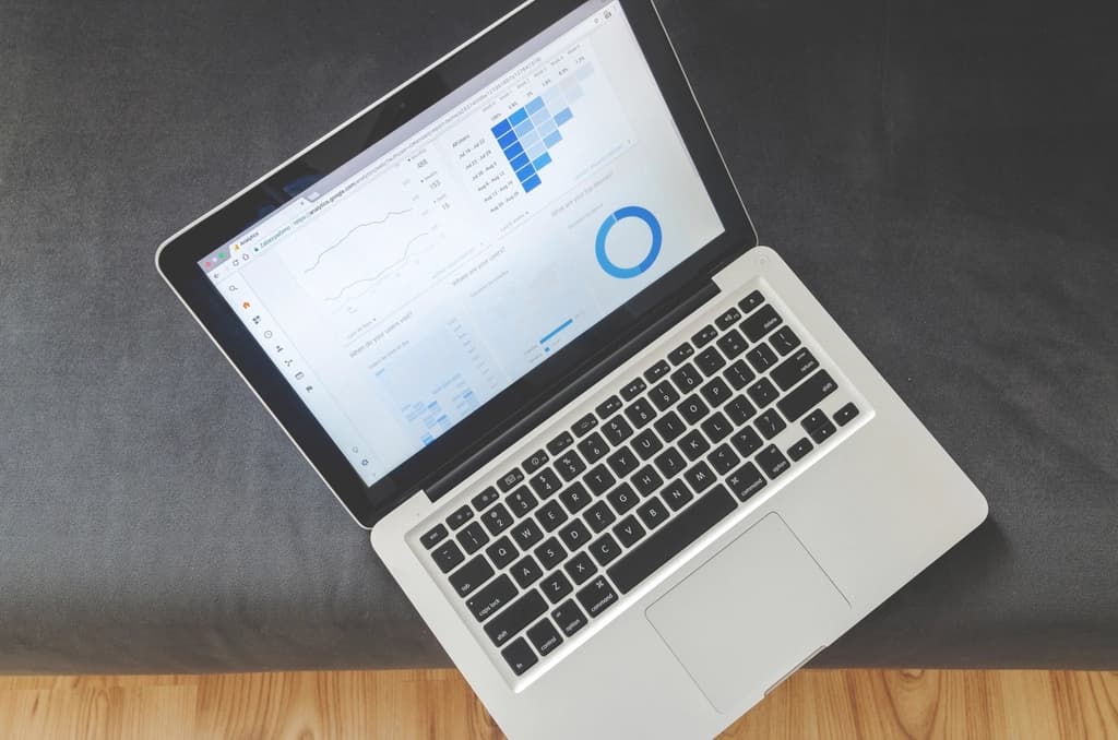 Open laptop on a grey couch showing an analytics dashboard with line graphs and a circular chart