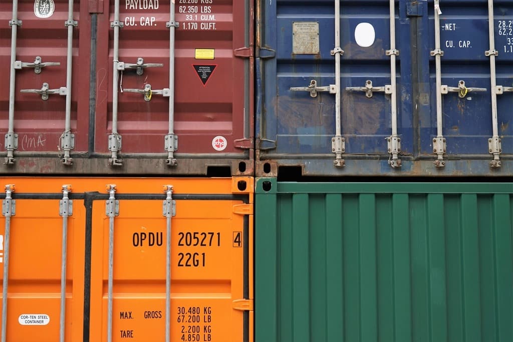 Close-up of stacked red, blue, orange and green shipping containers with export markings