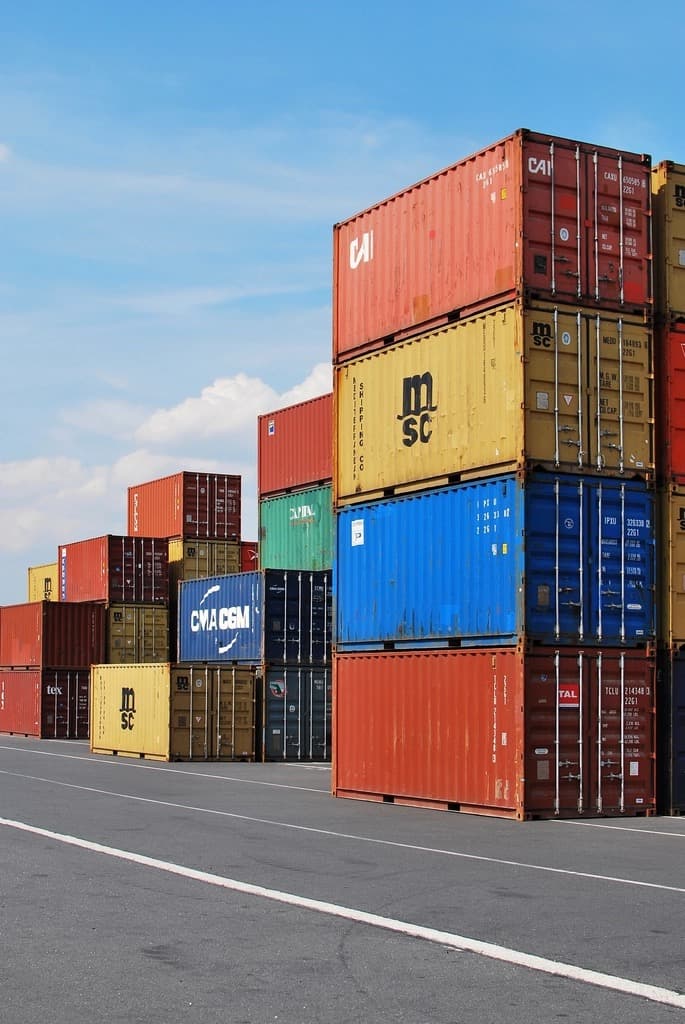 Colourful cargo containers stacked in a port yard under a blue sky