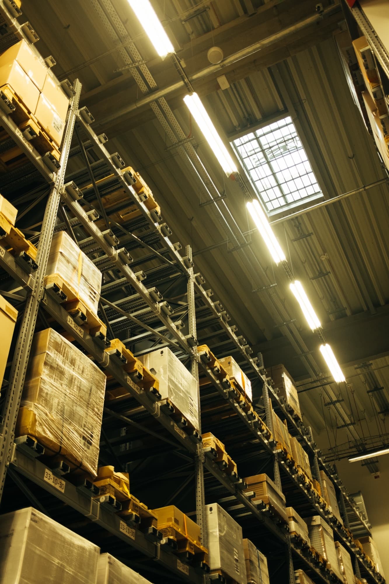 Tall warehouse racking stacked with labelled pallets and boxes
