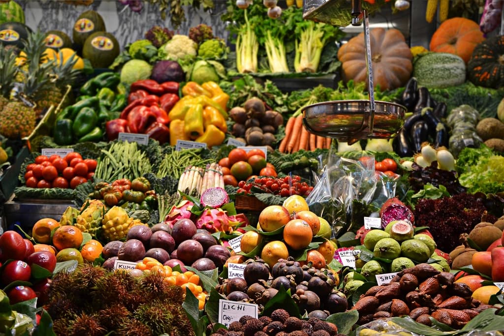 Vibrant market stall packed with fresh fruit and vegetables sorted into labelled sections ready for sale