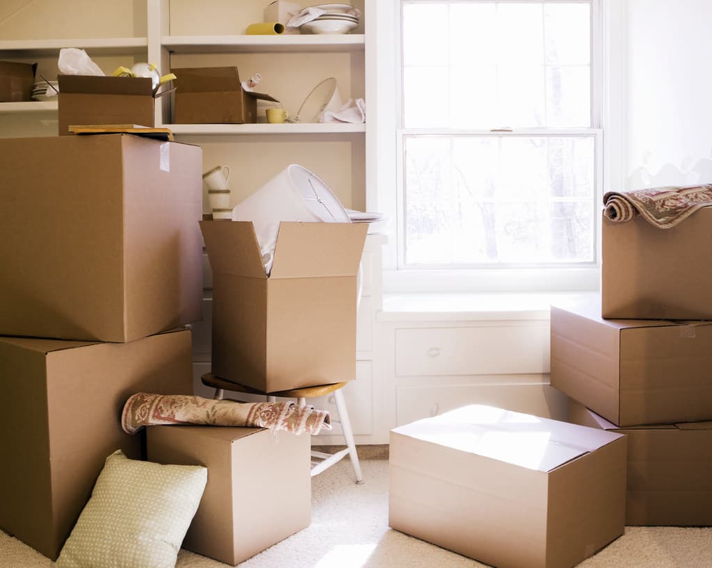 Stacked cardboard boxes packed and ready by a bright window