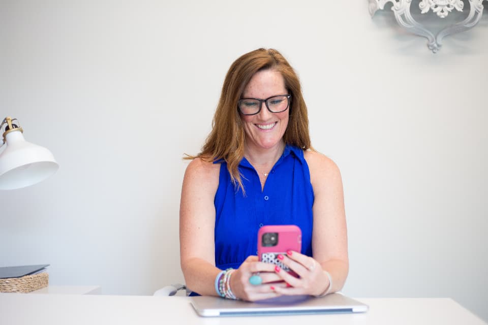 Person smiling while browsing a smartphone held in both hands