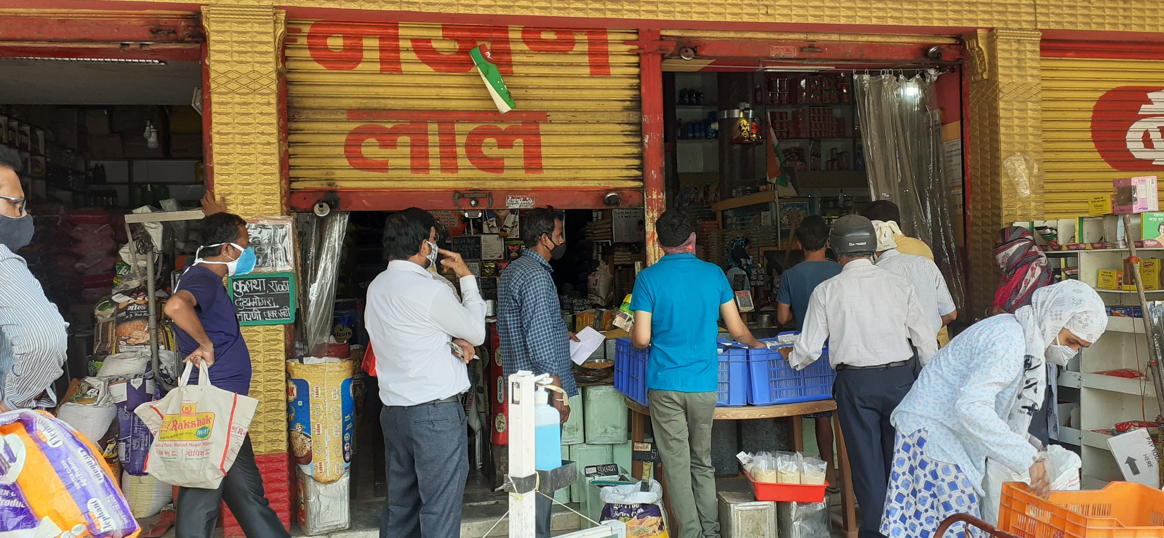 Customers buying from the counter of a busy Indian neighbourhood grocery storefront