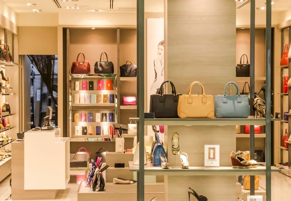 Premium boutique interior with designer handbags, wallets and shoes on softly lit display shelves