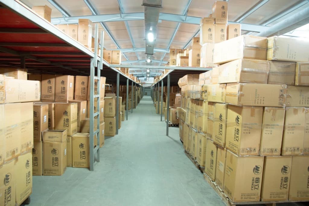 Long warehouse aisle stacked with sealed cardboard shipping cartons