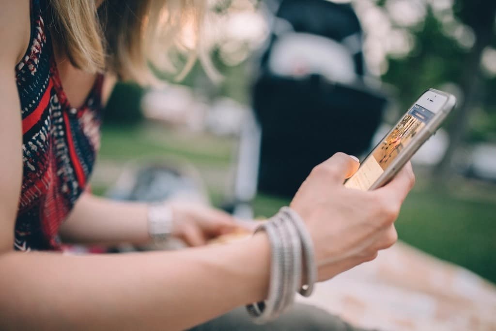 Young woman sitting outdoors browsing a social media feed on her smartphone