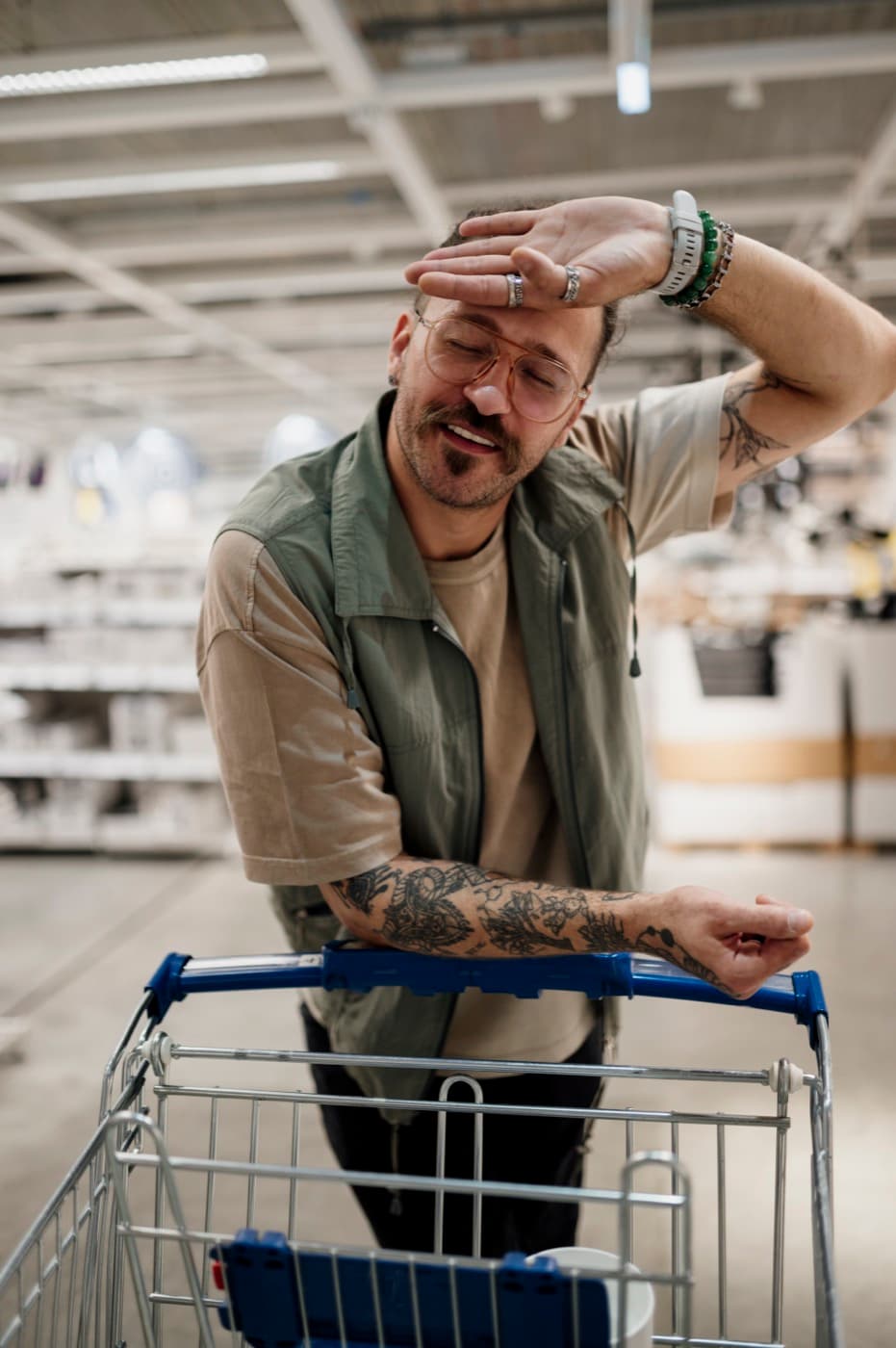 Casually dressed man leaning on a shopping cart inside a modern retail store aisle