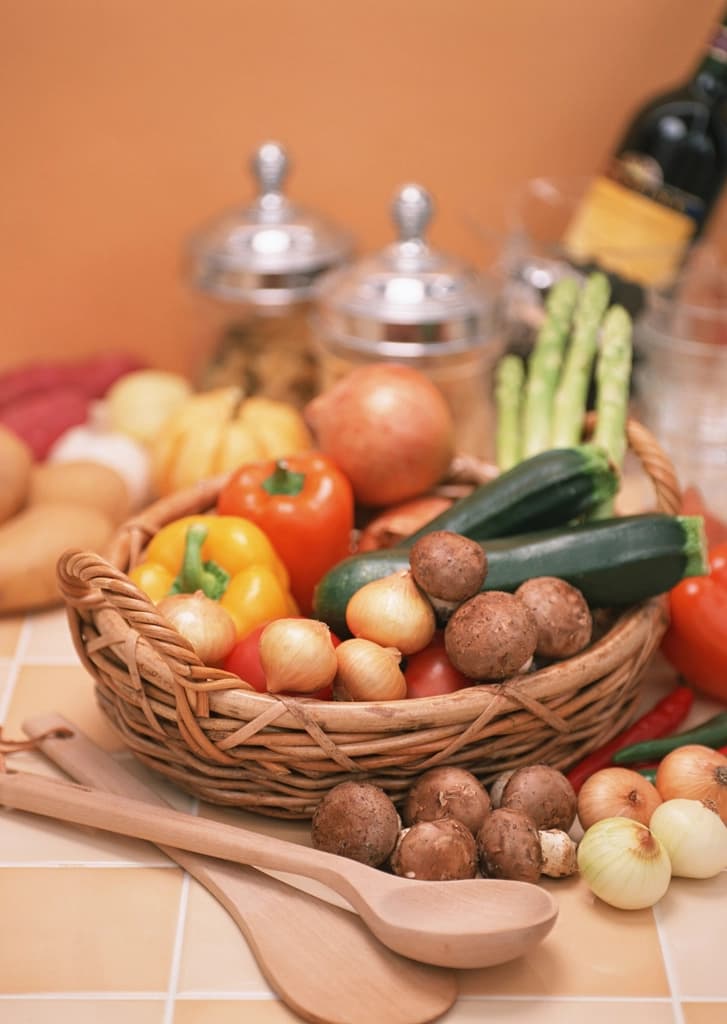 Wicker basket filled with fresh peppers, onions, mushrooms, zucchini and asparagus