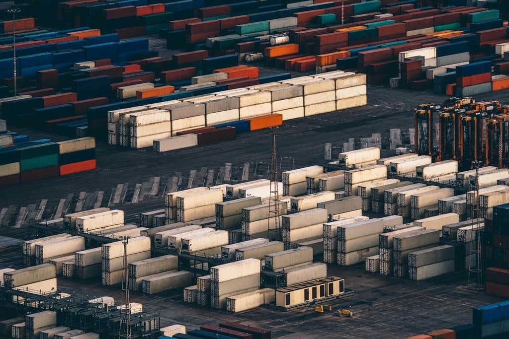 Aerial view of a container yard with rows of refrigerated and multicolored intermodal shipping containers stacked across a port storage area